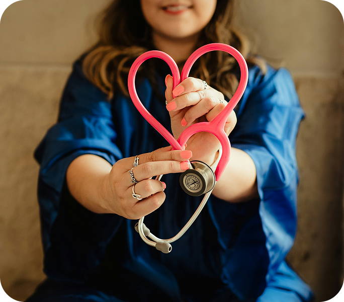 Healthcare professional in blue scrubs holding stethoscope shaped like a heart