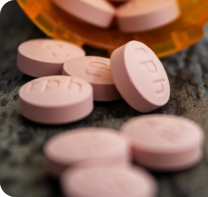 Pink medication tablets with amber bottle representing pharmaceutical compounding