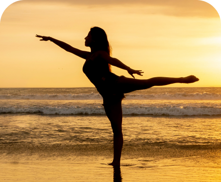 Silhouette of person in graceful yoga pose on beach at golden sunset