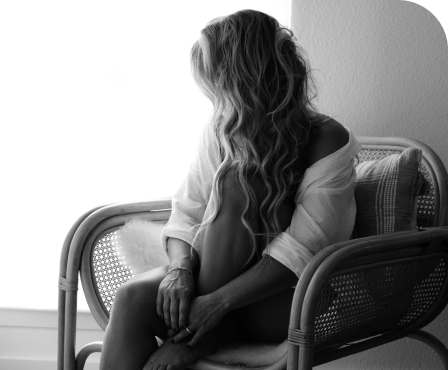 Woman with long wavy hair sitting thoughtfully in a wicker chair